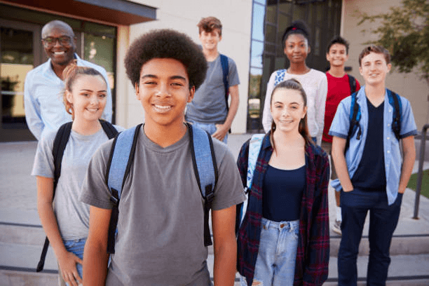 Diverse group of students of different ethnicities smiling together outside their school